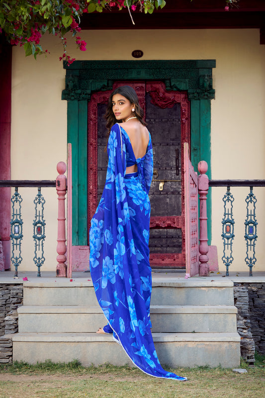 Woman wearing a flowing blue floral saree with a stylish backless blouse.