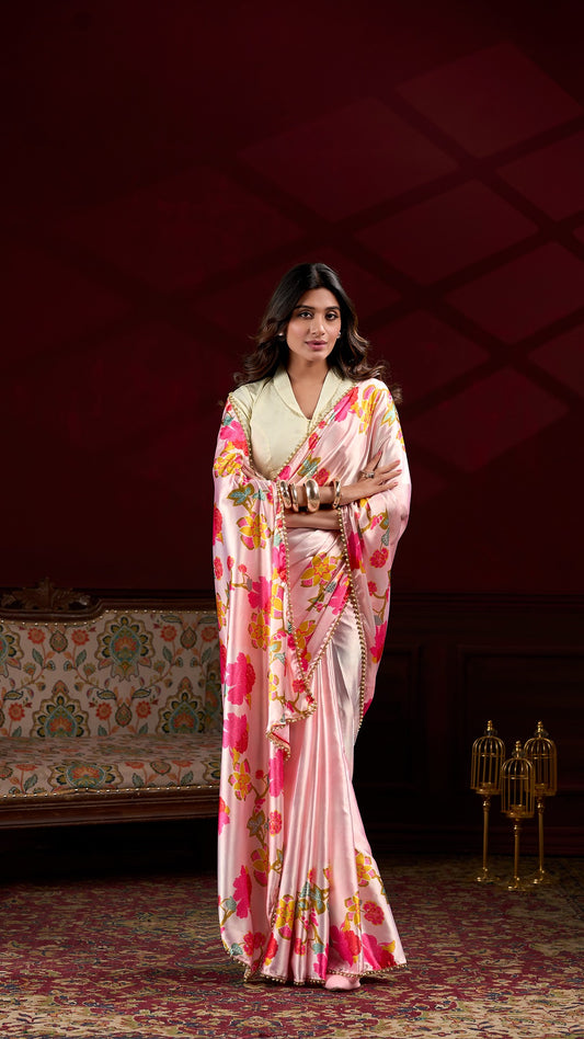 Elegant woman in a pink satin saree with floral print and lace trim.