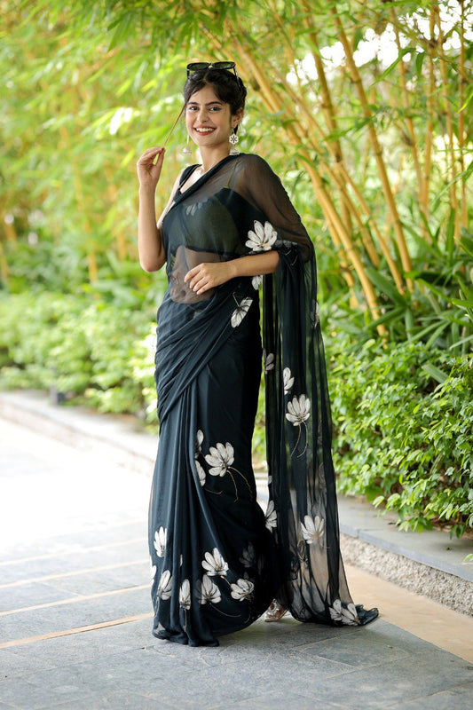 Elegant woman wearing a sheer black georgette saree with white floral design.