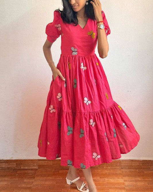 Model showcasing the pink Butterfly Maxi Dress with hand in pocket and comfortable cotton fabric.