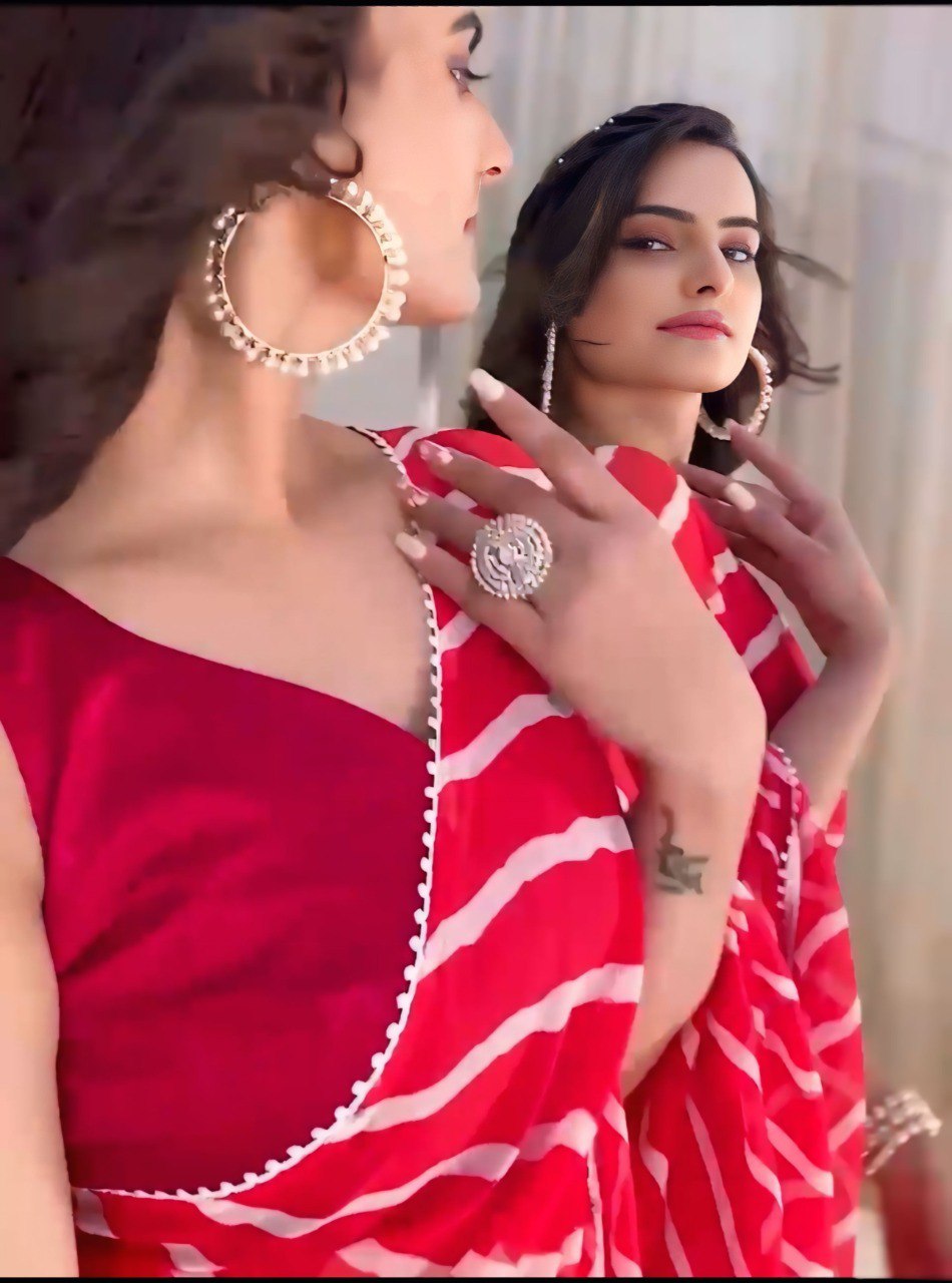 Close-up of a red leheriya print georgette saree with a sleeveless blouse and statement jewelry.