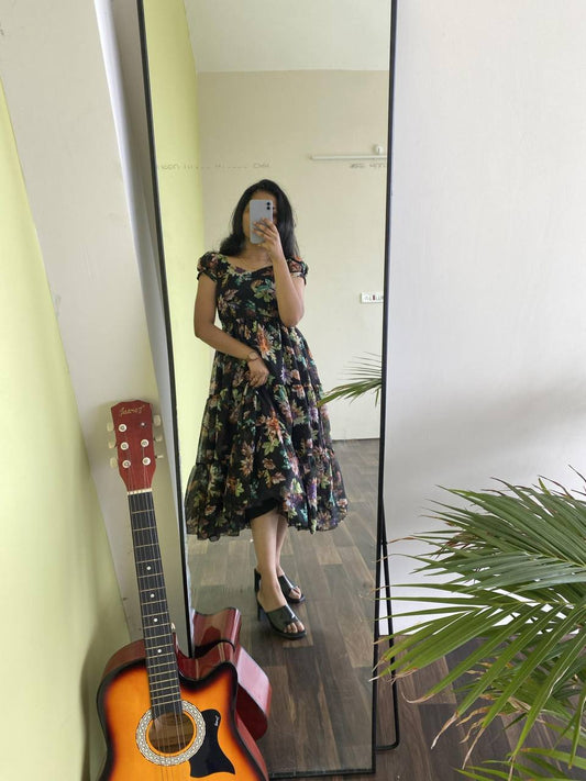 Full-length reflection of a woman wearing a black floral print 'Floral Getaway' dress.