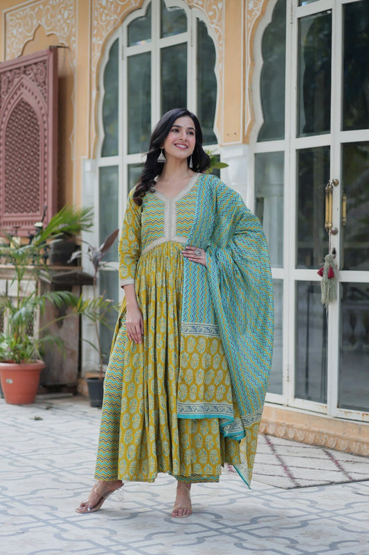 Mustard and teal block print cotton kurti set with chevron dupatta and V-neck lacework, model smiling outside.
