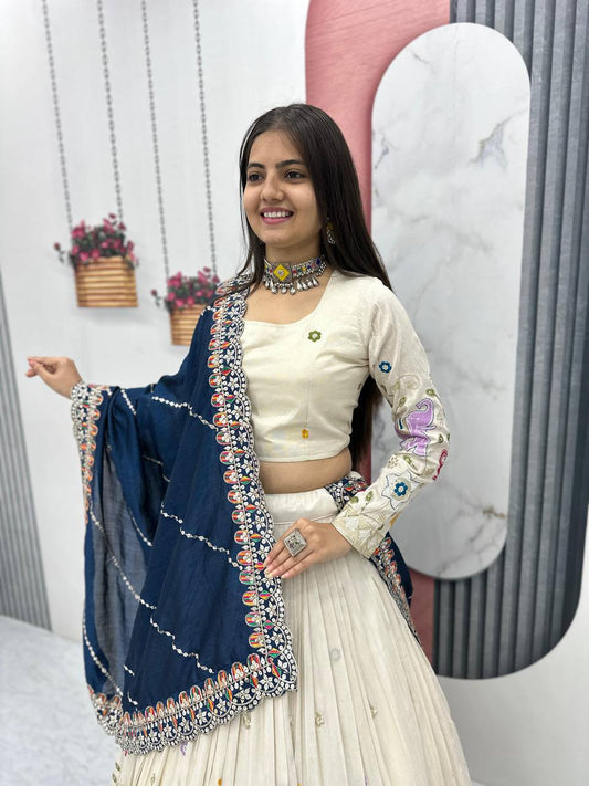 Close-up of a smiling woman in an embroidered off-white lehenga choli with a navy blue dupatta.
