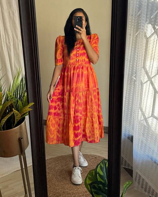Front view of a woman wearing the tiered Moringa Maxi dress in orange tie-dye.