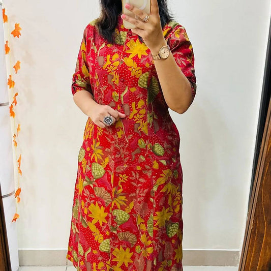 Woman wearing bright red floral A-line cotton kurti with elbow-length sleeves and bold yellow motifs.