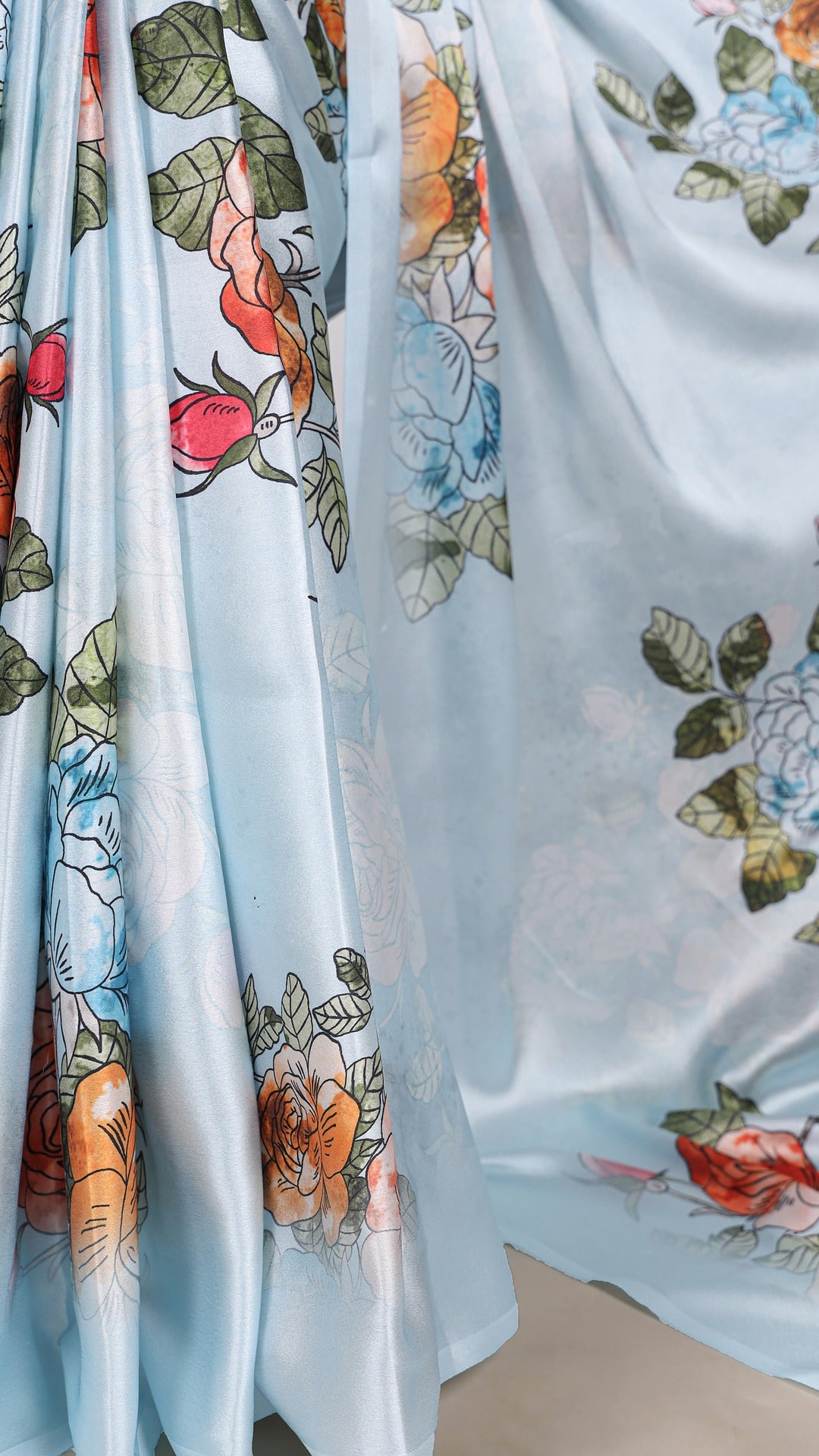 Flowing satin saree with colorful floral patterns.
