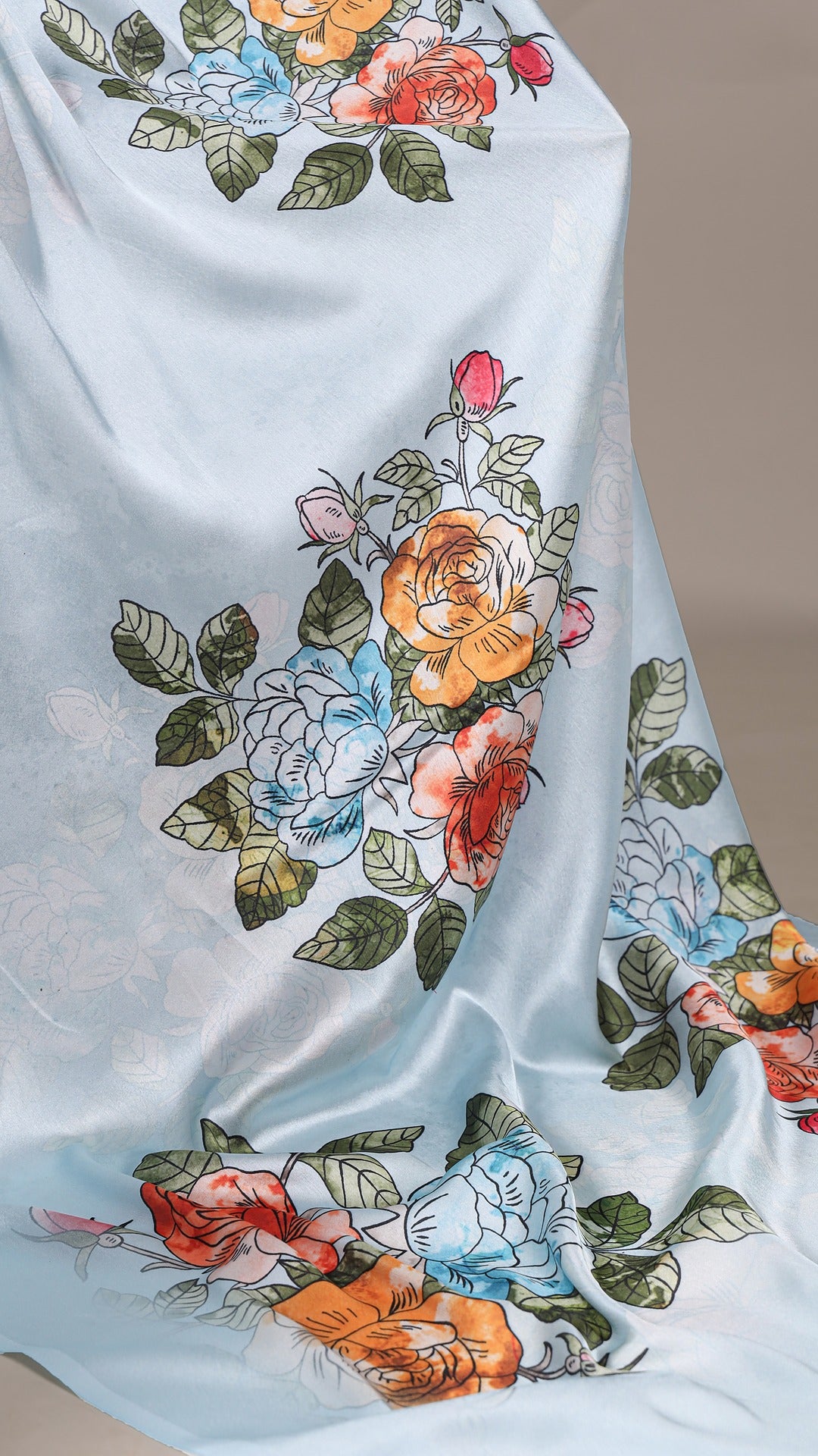 Close-up of floral print on a satin saree, light blue fabric.