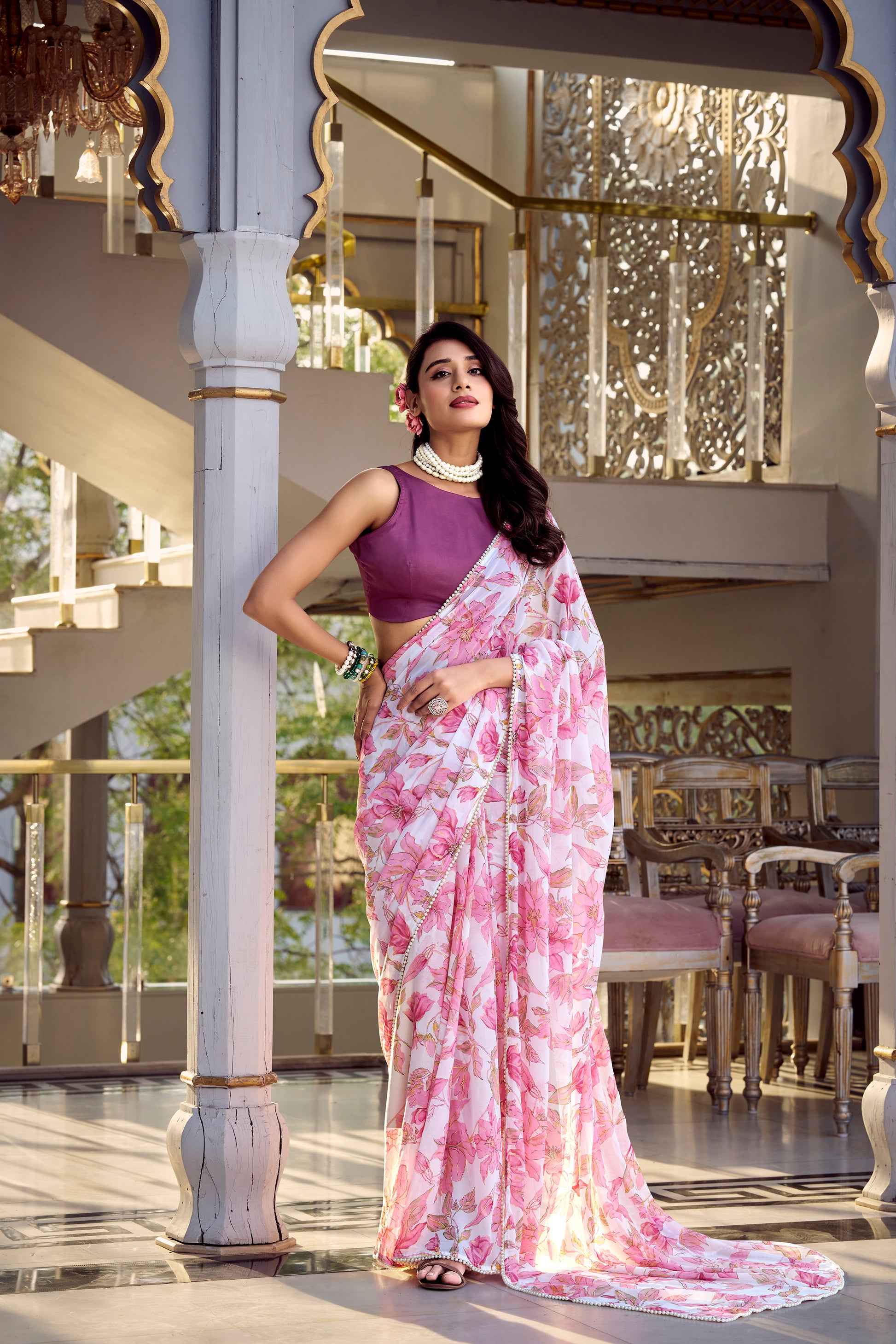 Model standing in a lilac pink floral saree with embellished border, looking elegant.