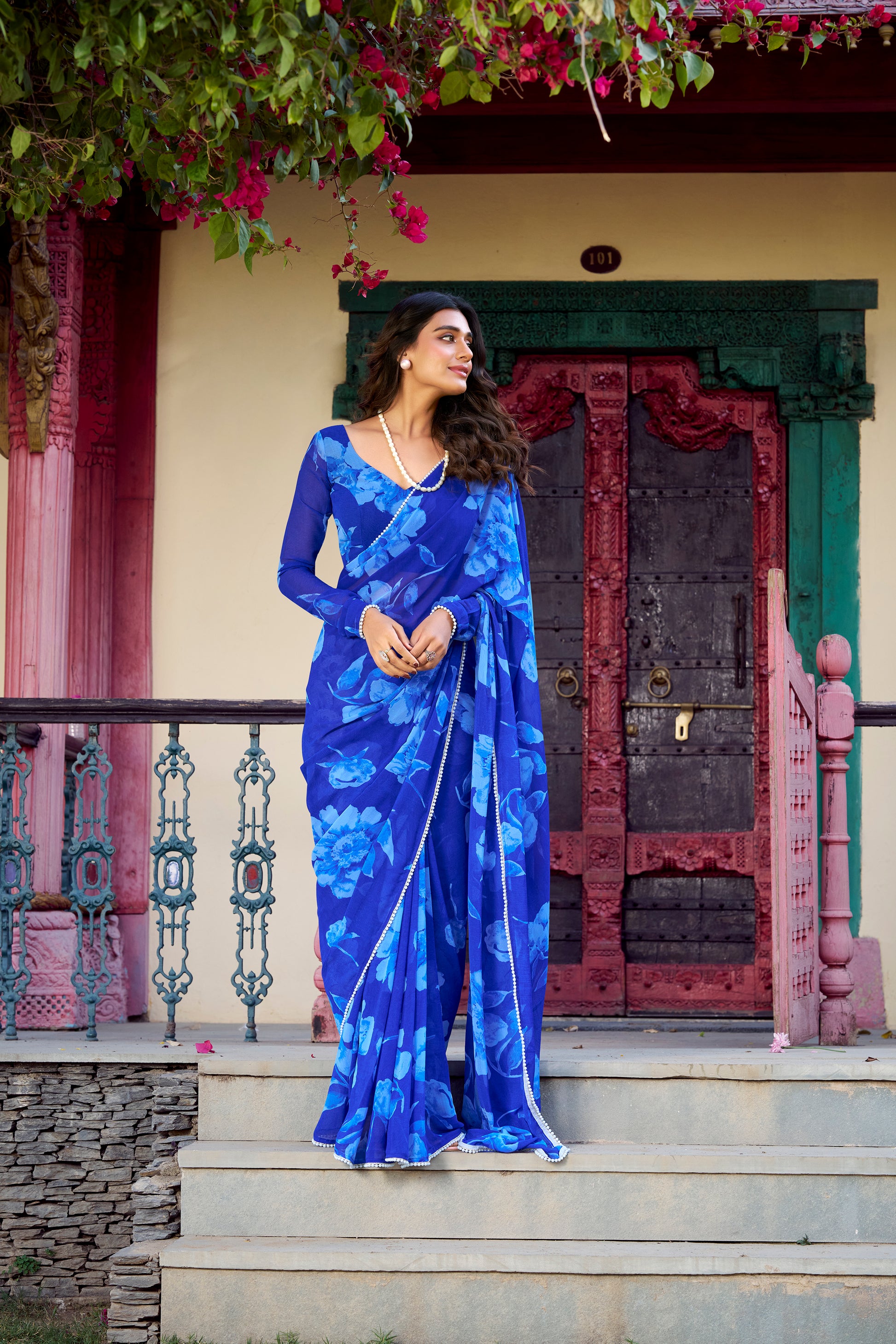 Model showcasing the full blue floral print saree with delicate pearl accents.