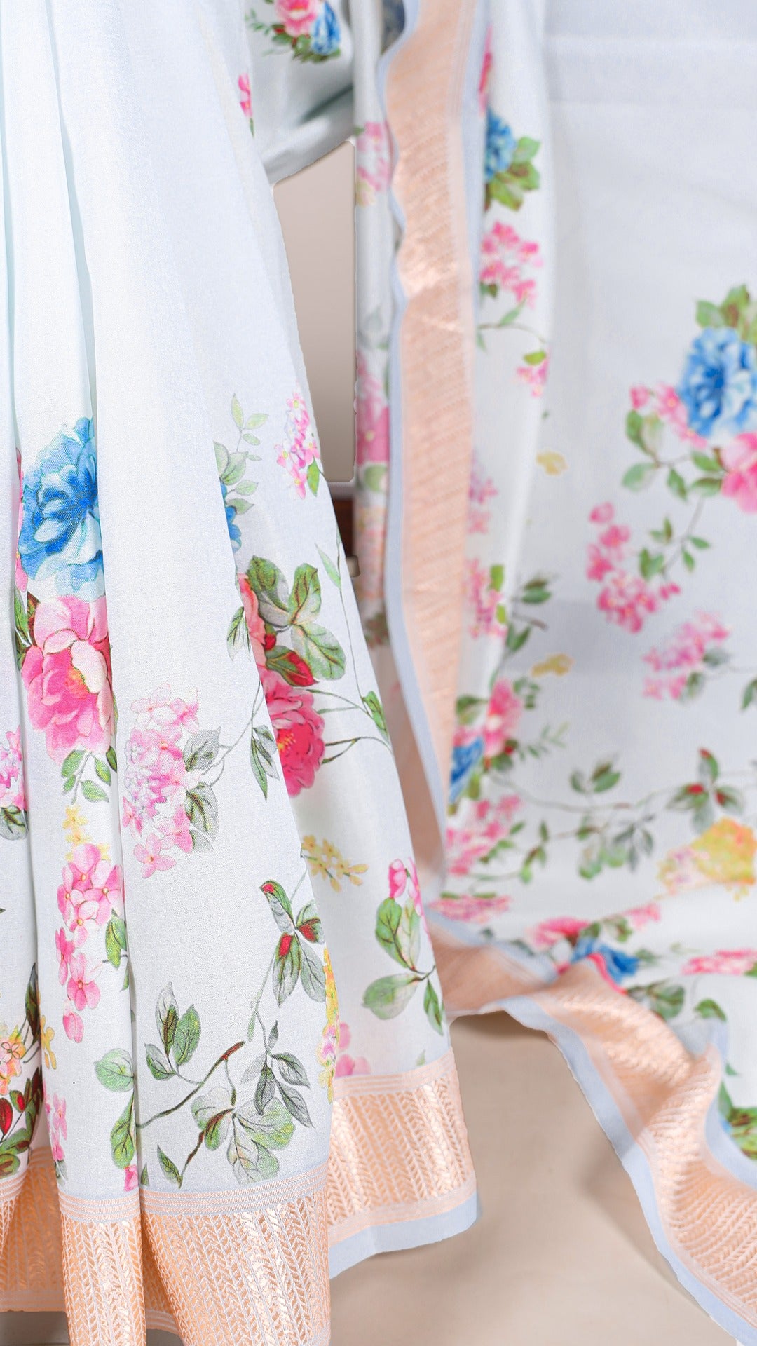 Detailed view of the floral print and woven border on the light blue saree.