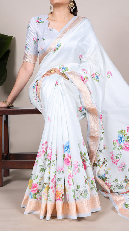 Model in sky blue floral saree with matching blouse and gold jewelry.