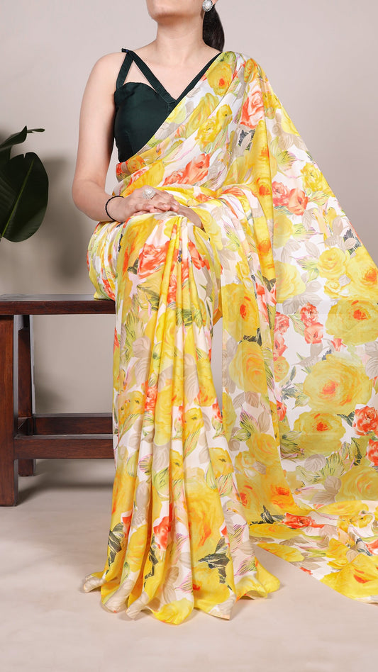 Woman in a yellow floral satin saree, seated elegantly.