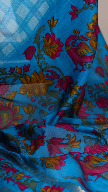 Close-up of blue saree fabric with floral and peacock print.