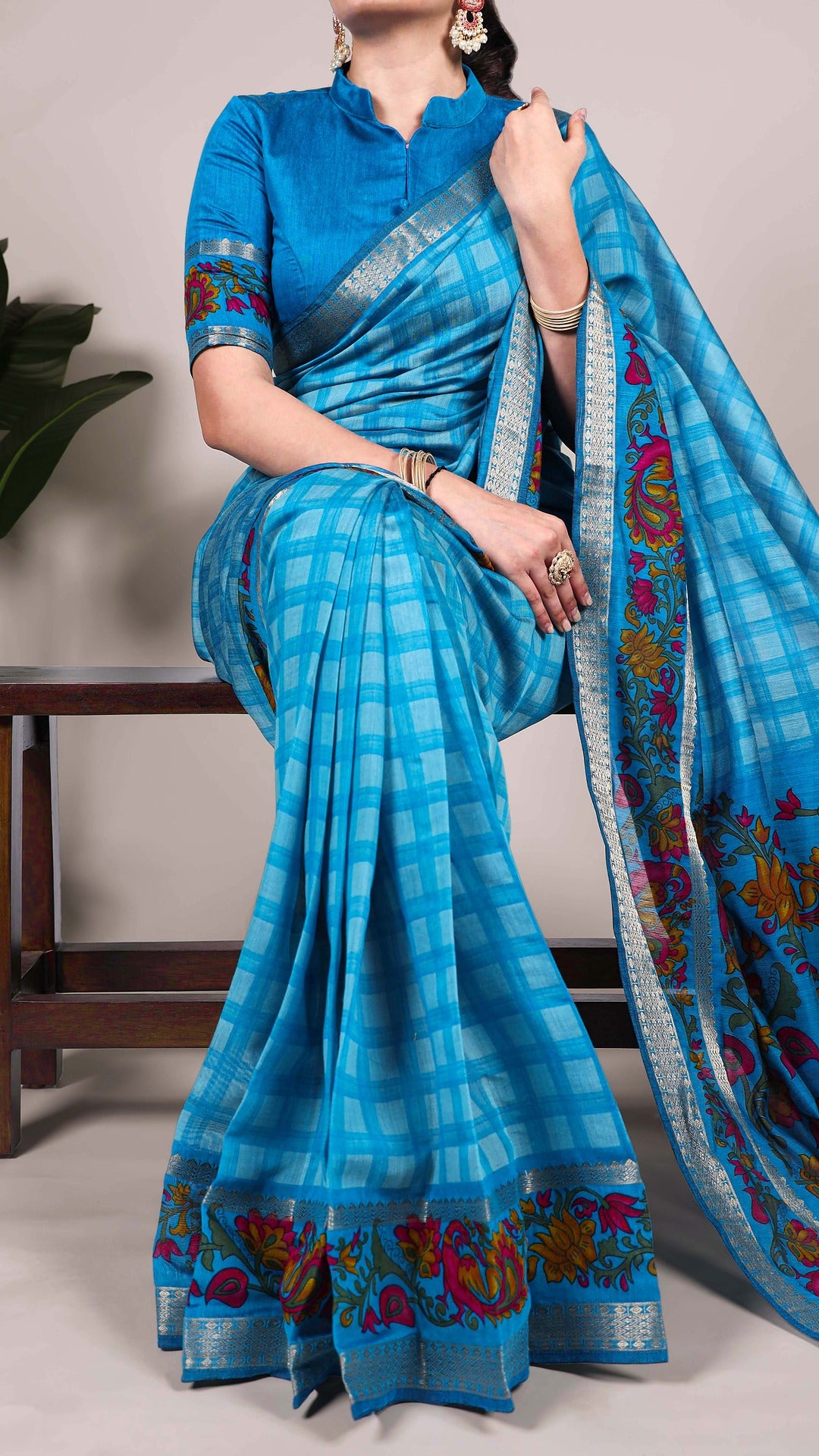 Woman wearing blue checked saree with floral details.