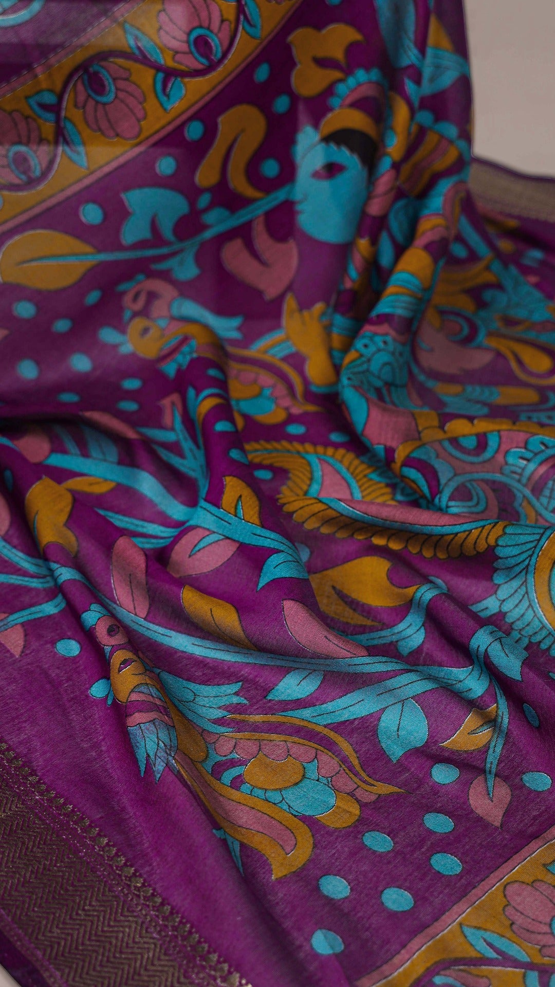 Close-up of purple saree fabric with intricate floral design.