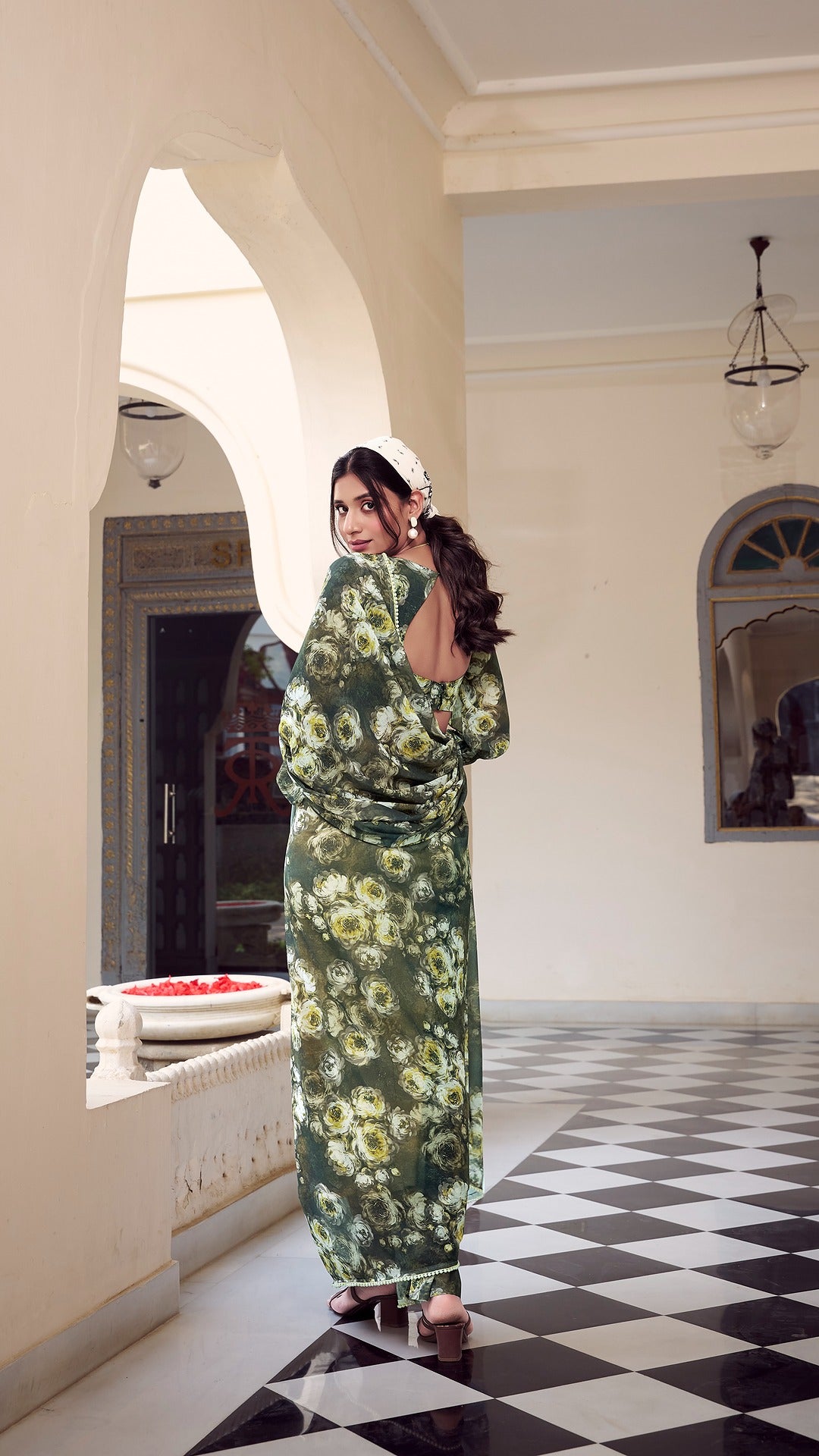 Woman wearing a green floral saree with stylish open-back blouse design.