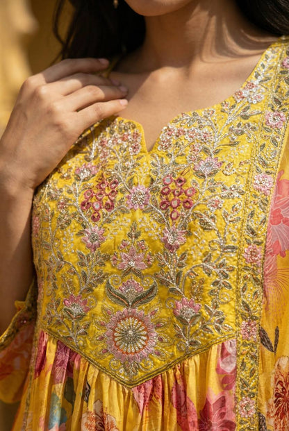 Close-up of a yellow crepe kaftan featuring intricate pink floral embroidery and sequin detailing.