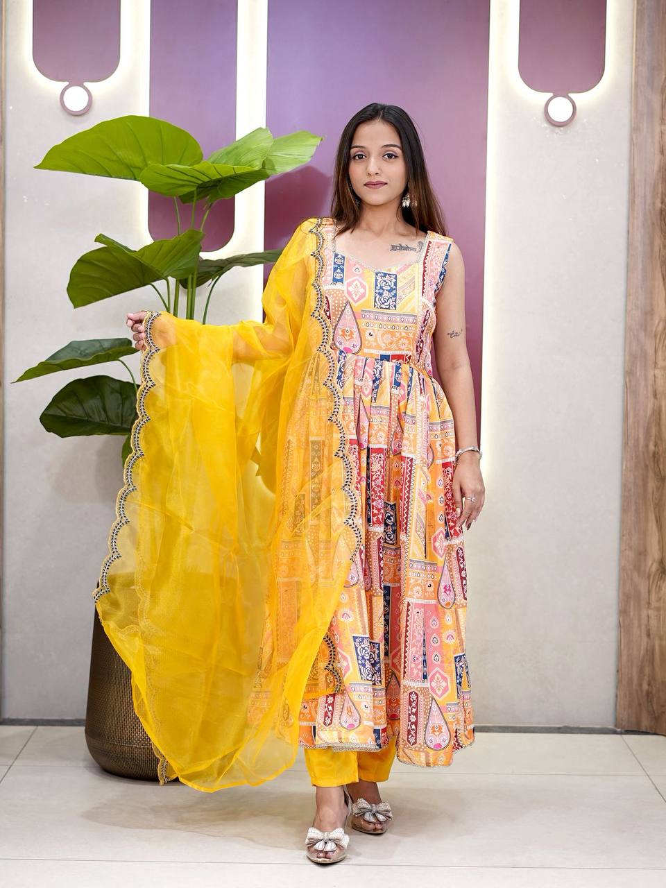 Elegant yellow Anarkali suit set with vibrant prints and sheer dupatta.