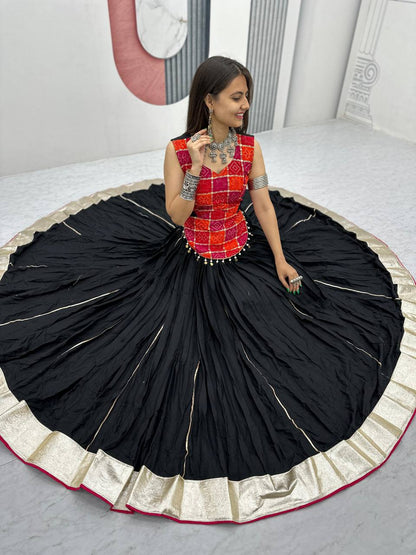 Top view of woman sitting in full flair black lehenga and bright red choli, highlighting large skirt spread.