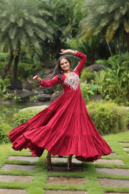 Woman twirling in maroon Kutchi embroidered Gamthi Gown, showcasing dramatic flair and festive style.