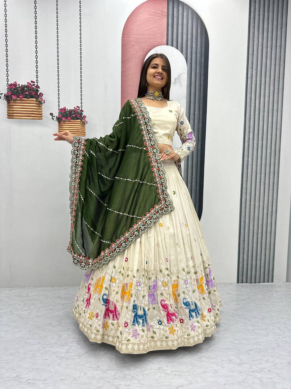 Woman in an off-white lehenga choli with elephant embroidery and an olive green dupatta.