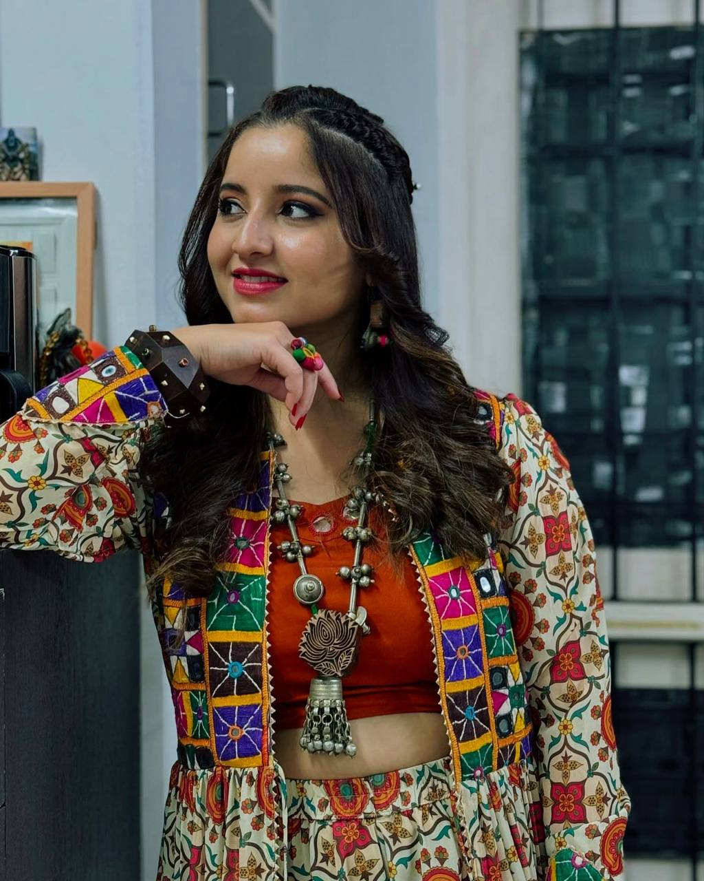 Woman smiling in Kachchi Charm lehenga choli set with intricate embroidery and colorful mirror work shrug.
