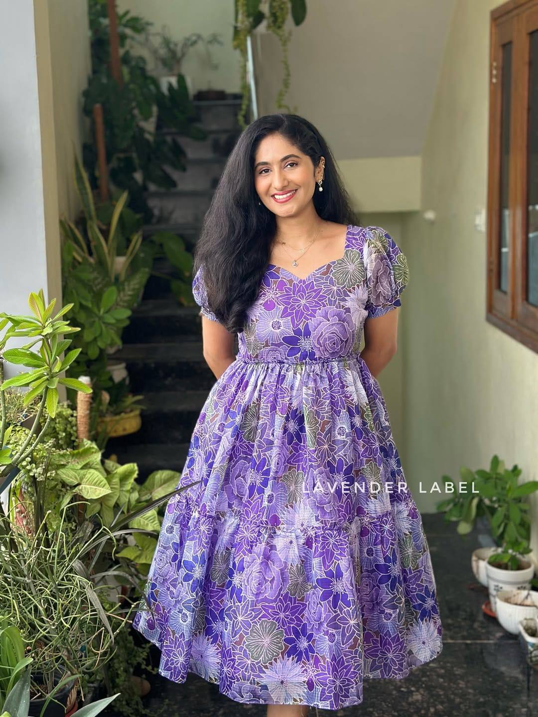 Close-up of purple floral print maxi dress in sunlight with greenery.