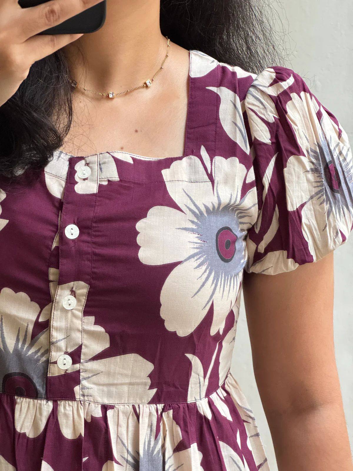 Close-up of square neckline and puffed sleeves on maroon floral dress.