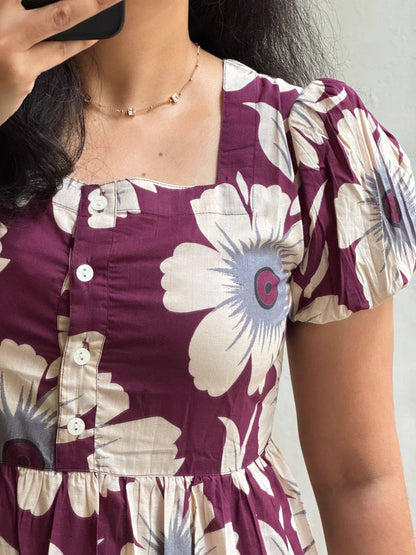 Close-up of square neckline and puffed sleeves on maroon floral dress.