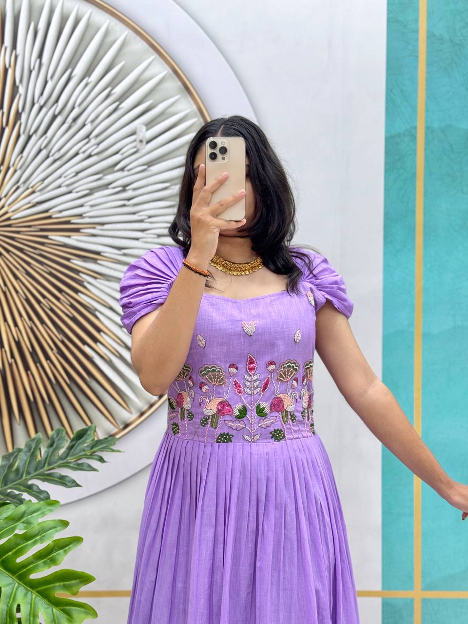 Close-up of the purple and violet handworked gown showing the detailed floral embroidery.