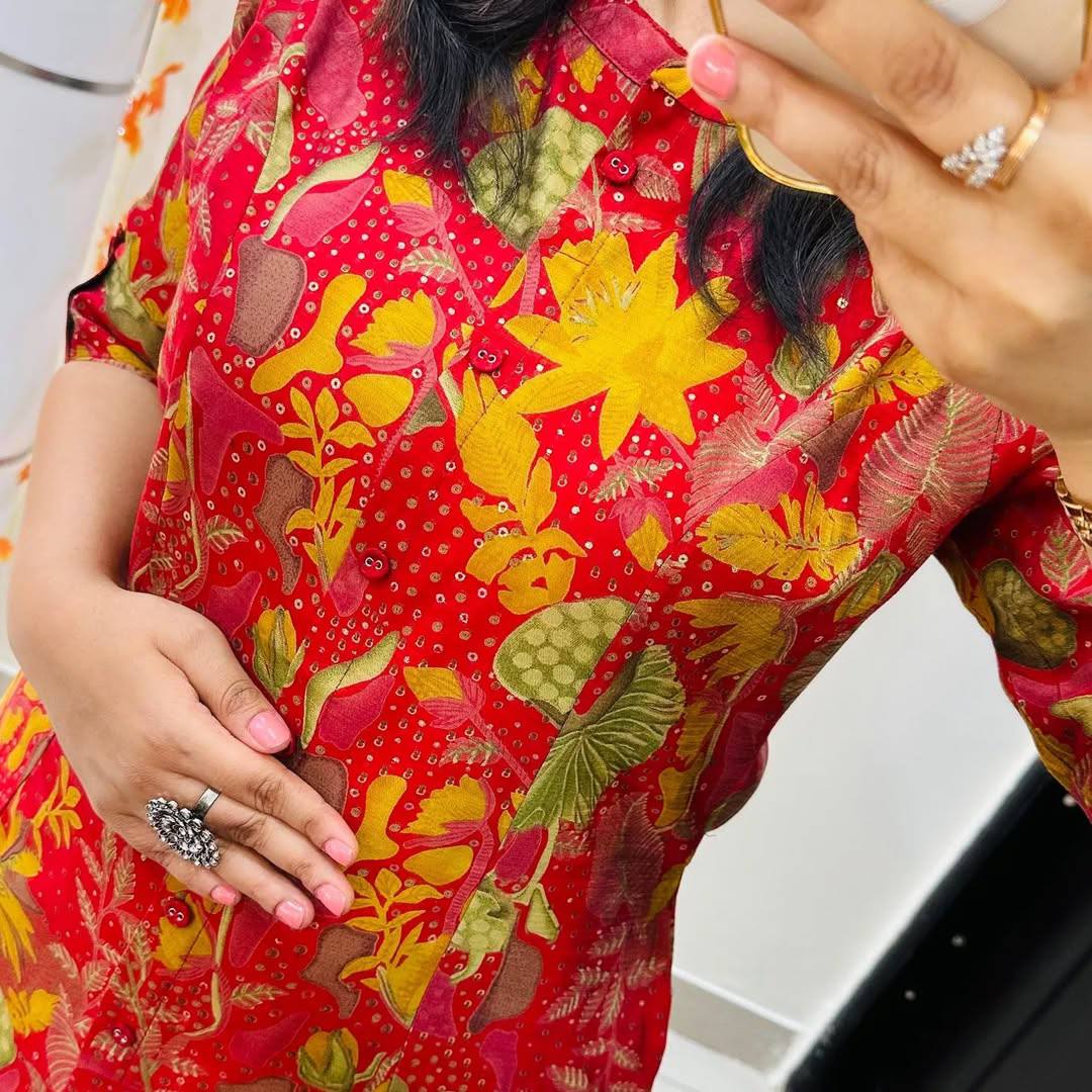 Close-up of multicolor floral print and button placket on red cotton kurti, showing fine details.