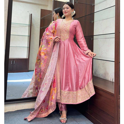Woman in elegant pastel pink Anarkali suit with detailed embroidery and floral dupatta.