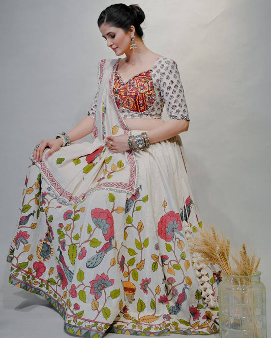 Seated woman in ivory cotton lehenga choli, vibrant mirror-embroidered blouse, and folk print skirt for Navratri.