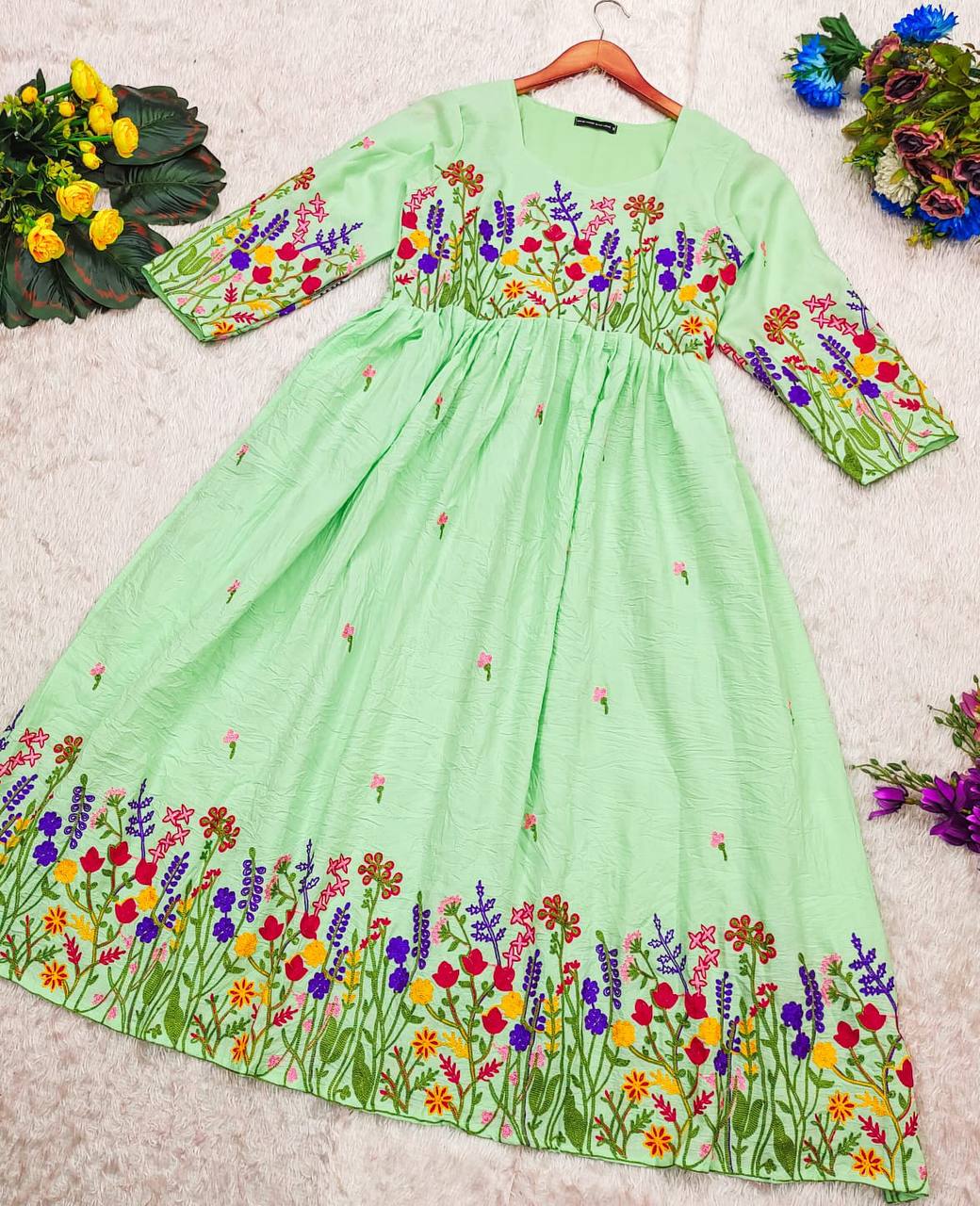 Full view of the light green Maska Cotton Dress with floral embroidery on a hanger.