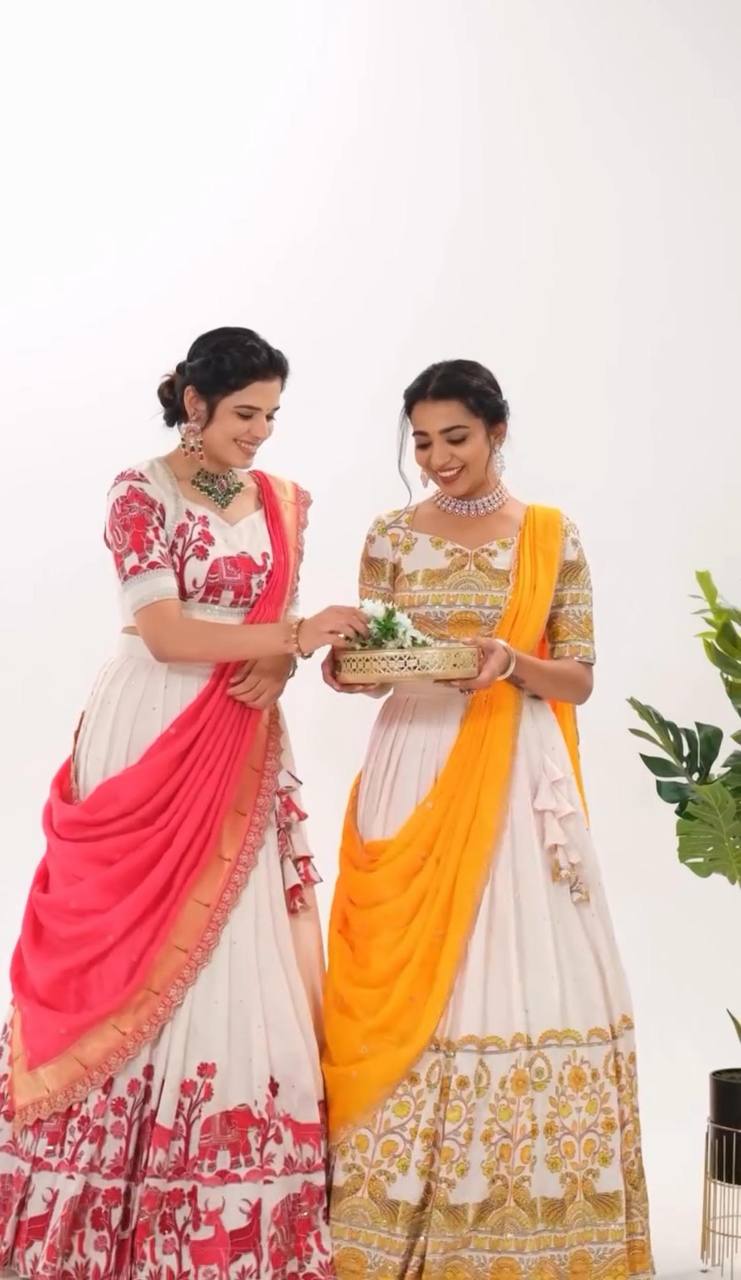 Two models wearing Kalamkari lehenga choli sets in yellow and red.