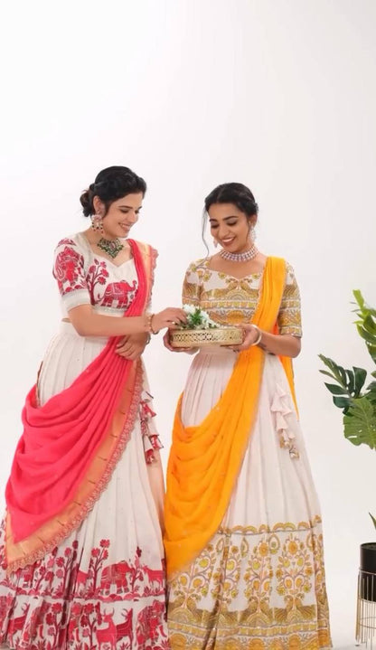 Two models wearing Kalamkari lehenga choli sets in yellow and red.