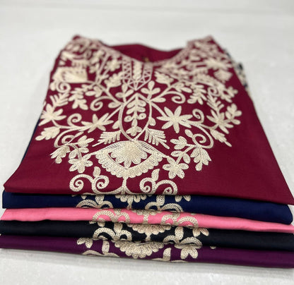 Stack of folded Adaa ShortKurtis in maroon, blue, pink, black, and purple, all with signature floral embroidery.