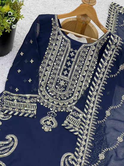 Detailed view of navy blue kurta’s gold threadwork and sequin embroidery, with dupatta on hanger.