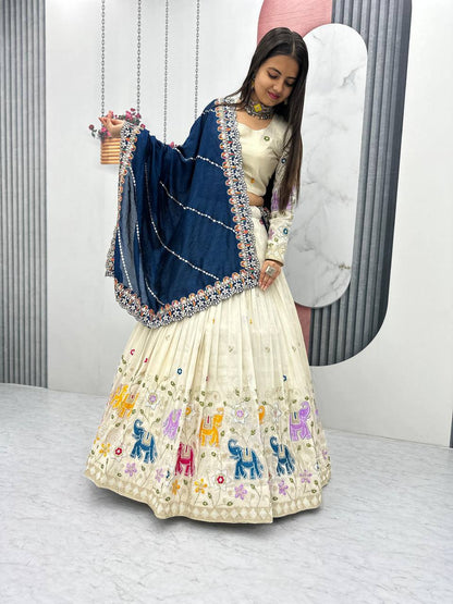 Woman in off-white lehenga choli with colorful elephant embroidery and a navy blue dupatta.