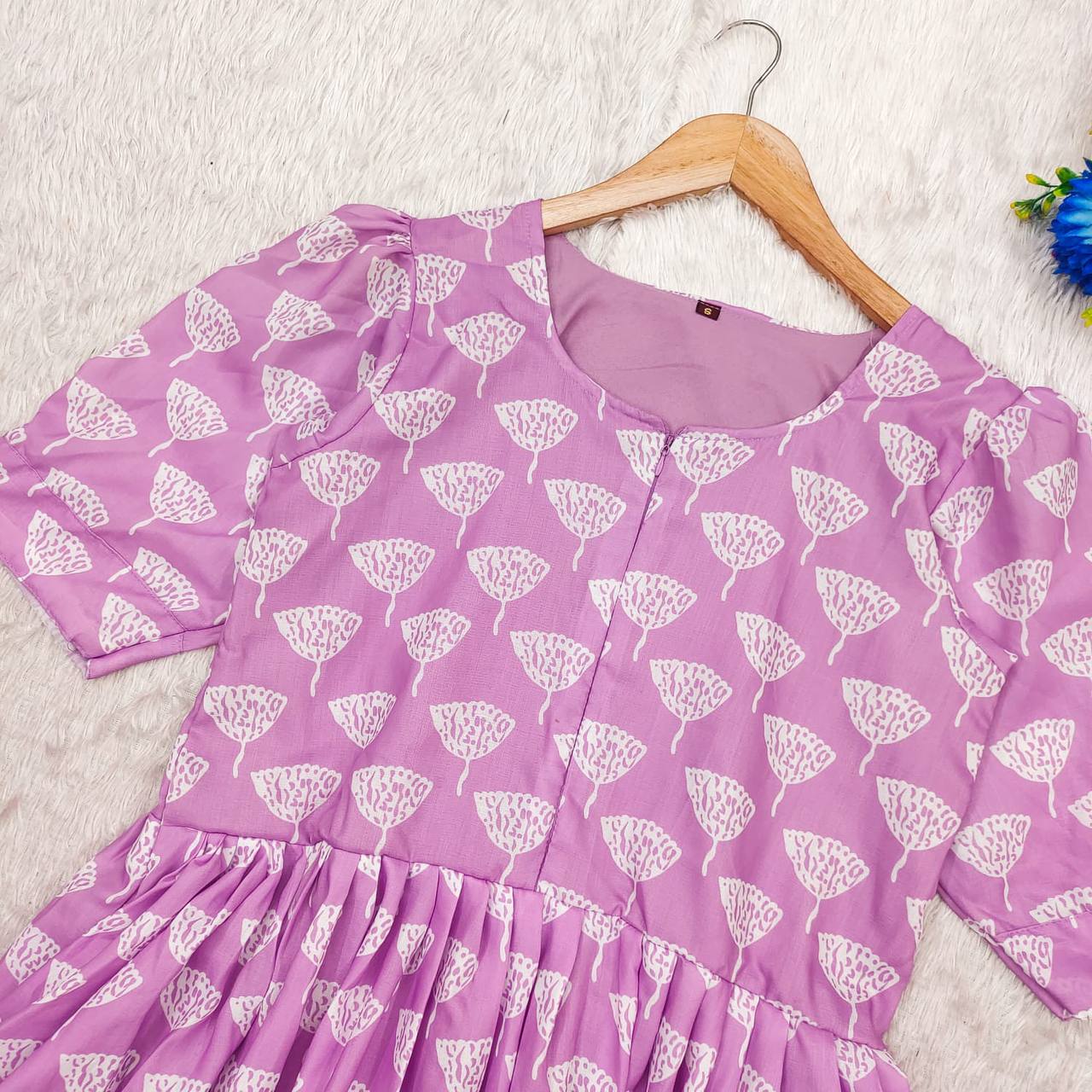 Lilac Ghibli Maxi dress on a hanger, showcasing the dress's top portion and pleated skirt.