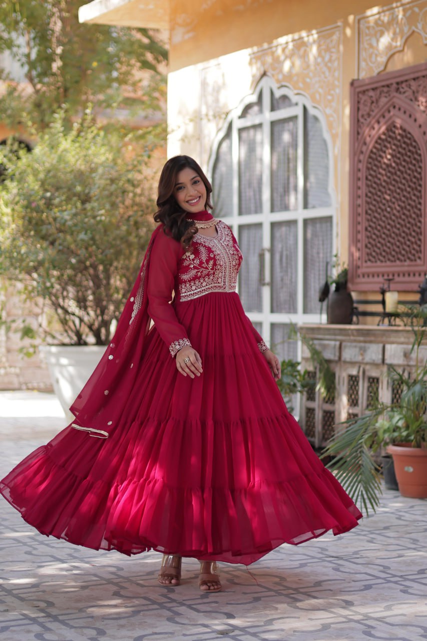 Woman twirling in a stylish red embroidered Georgette gown.