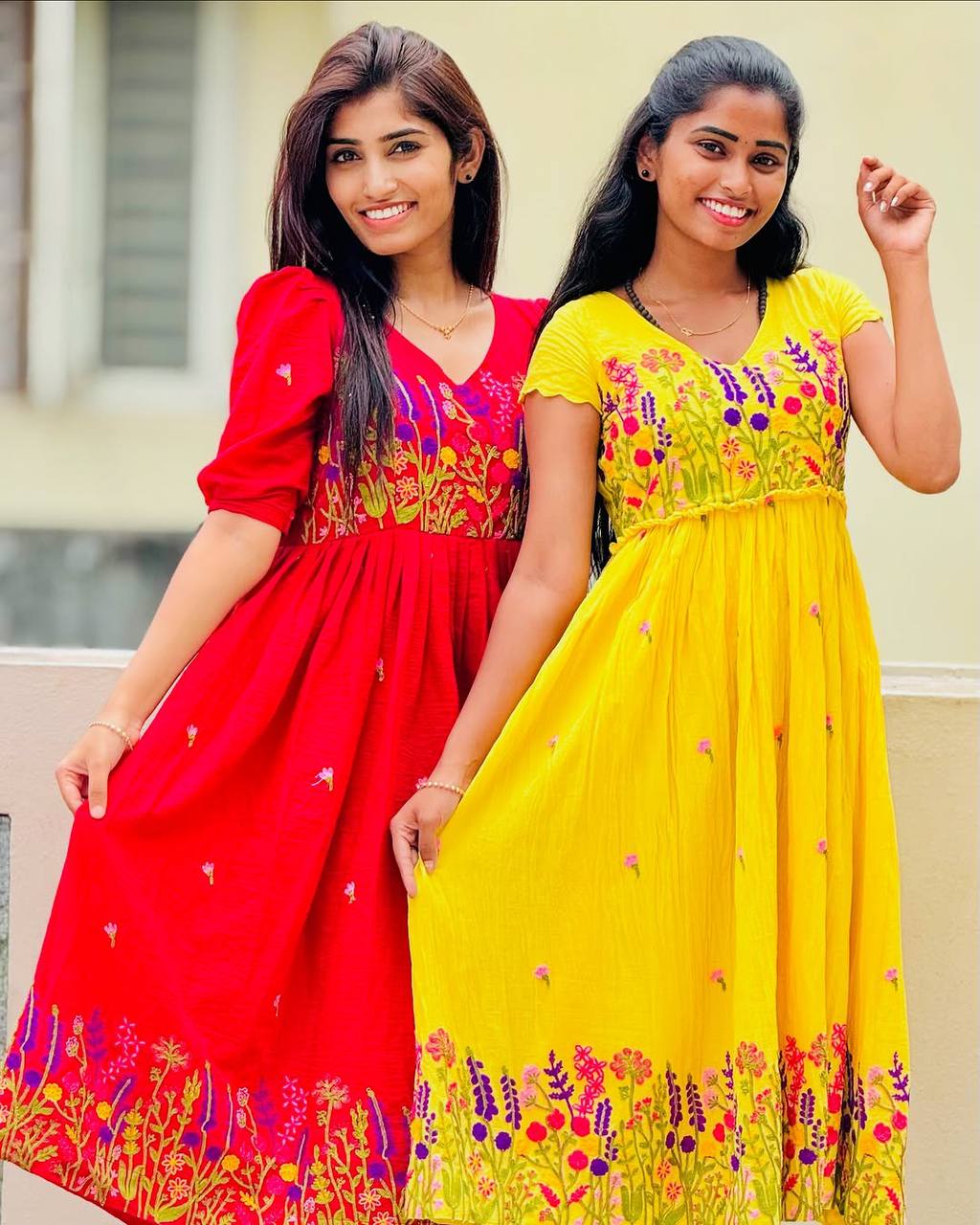 Models showcasing the Rangbhoomi Floral Embrace dresses in vibrant red and cheerful yellow.