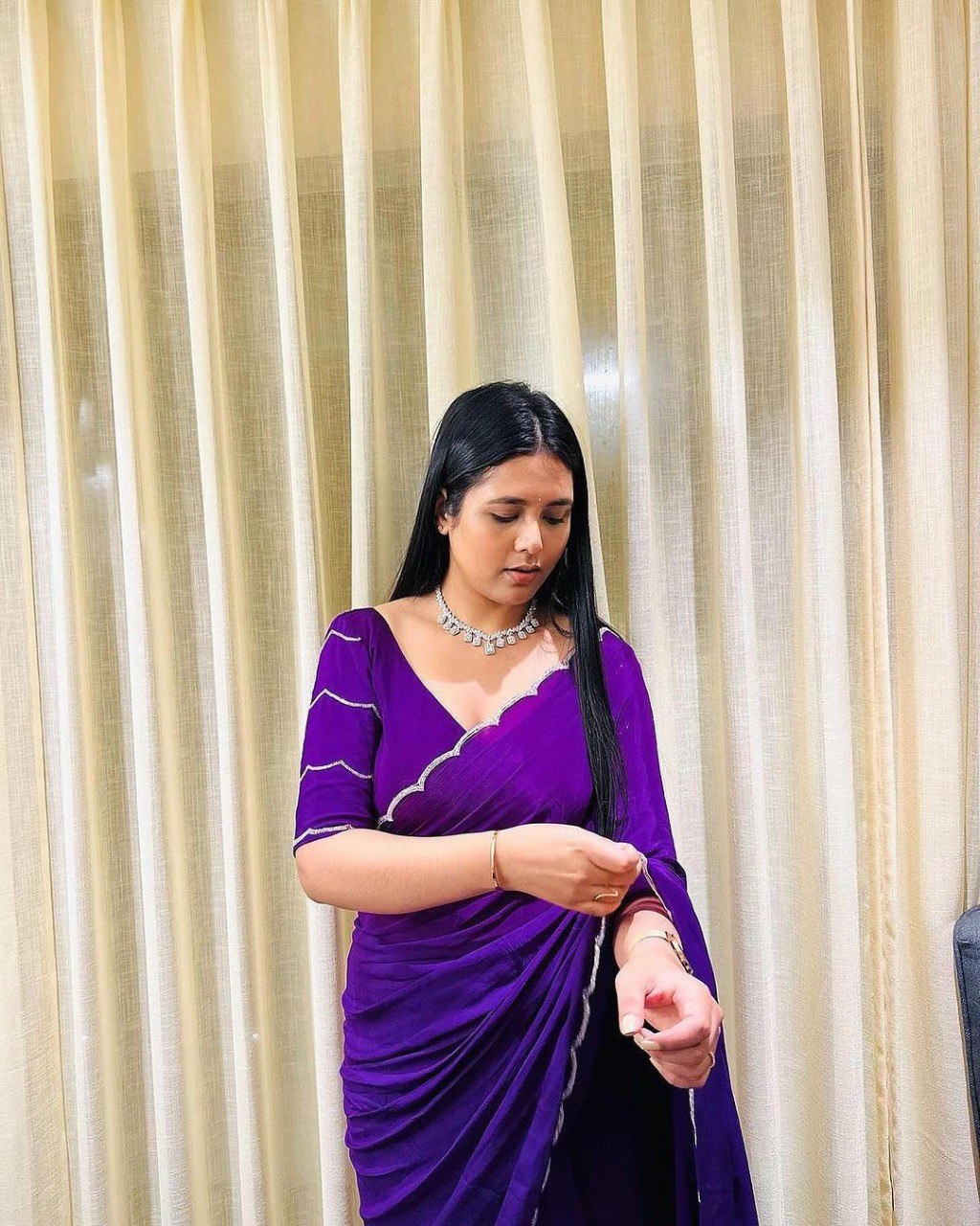Woman taking a mirror selfie in a stylish purple georgette saree.