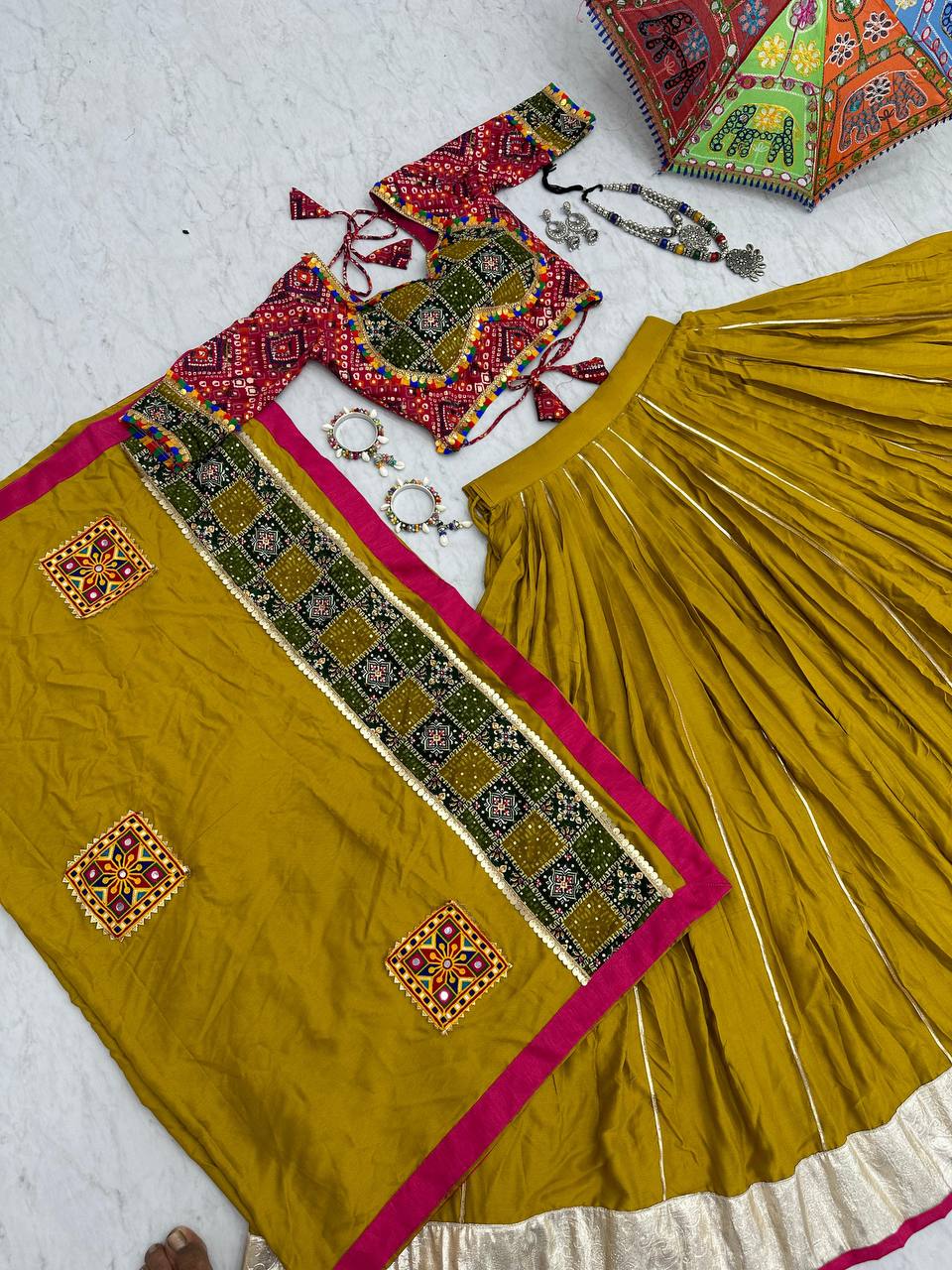 Full cotton lehenga choli set with Gamthi work, pink trim and gold border, laid on floor.