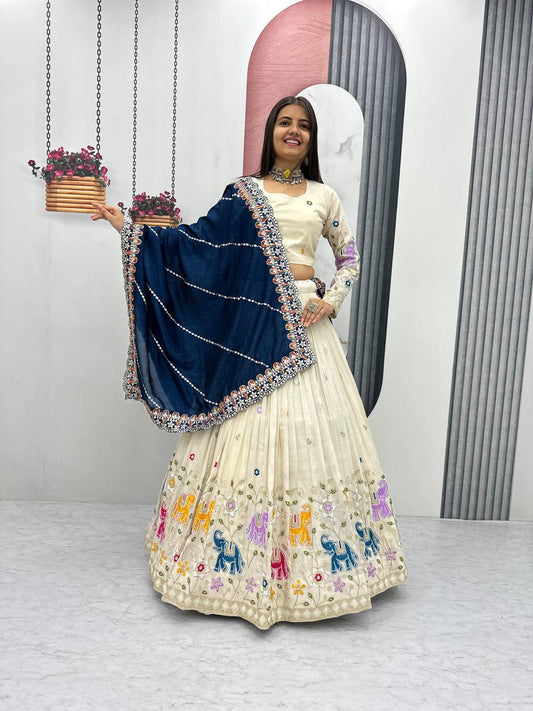 Woman wearing an off-white lehenga choli with elephant embroidery and a navy blue dupatta.