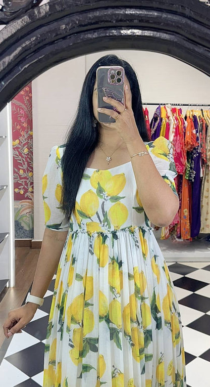 Woman in lemon print maxi dress with puffed sleeves and round neckline.