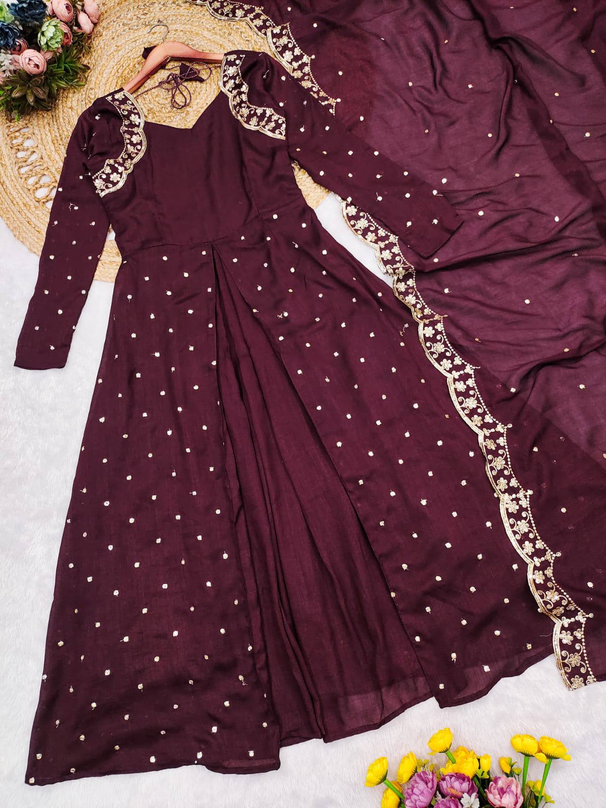 Model in a wine-colored Anarkali gown with gold detailing and matching dupatta outdoors.