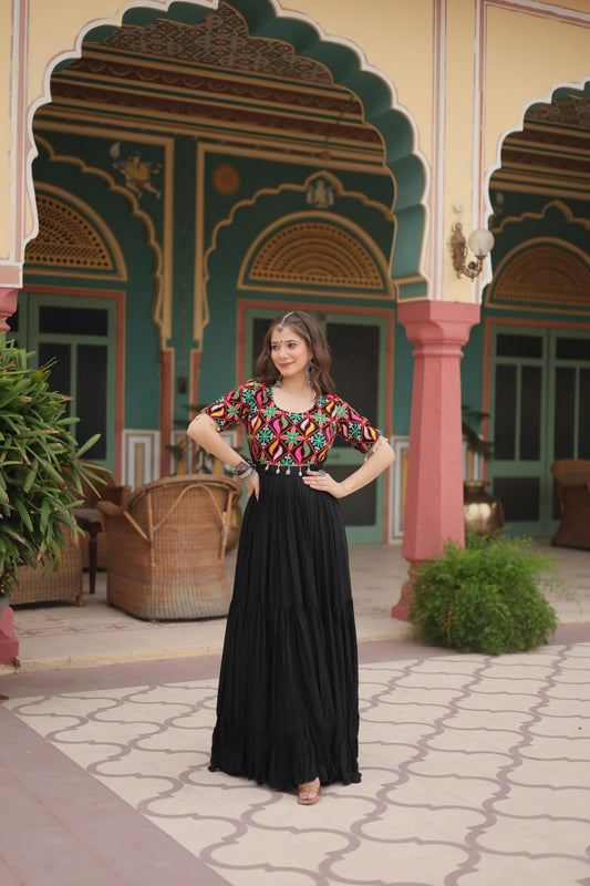 Boho Radiance black gown with vibrant Kutchi embroidery, worn by woman posing in festive courtyard.
