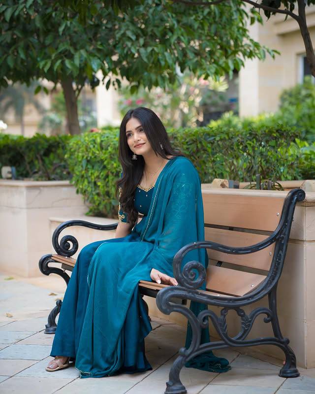 Model sitting on bench wearing teal Morpankh Anarkali with dupatta.
